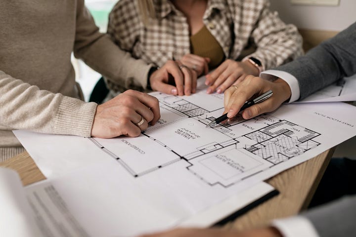 Real estate professionals reviewing a house floor plan, illustrating document processing and planning in the real estate industry.